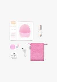Foreo LUNA 3 Plus en silicone rose avec des nœuds surélevés, câble de chargement USB, sérum, étiquettes rondes et un pochon rose à cordon.