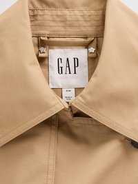 Col échantillon beige avec une étiquette indiquant "GAP SANDY LIANG," présentant des accents en forme d'étoile au niveau du col et des détails de couture visibles.