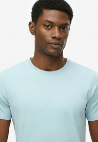 Lichtblauwe katoenen T-shirt met een ronde halslijn en korte mouwen, met een gladde textuur en een simpel ontwerp zonder patronen.