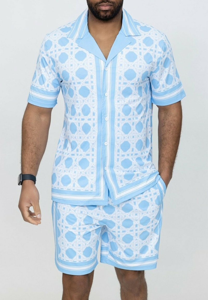 Chemise à manches courtes avec boutons et short assorti en bleu clair, ornés de motifs géométriques blancs et d'accents rayés. Tissu en coton, coupe décontractée.