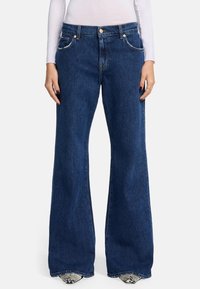 Jeans a zampa d'elefante blu scuro realizzati in denim, con tasche frontali, chiusura con bottone e cuciture a contrasto lungo le cuciture.