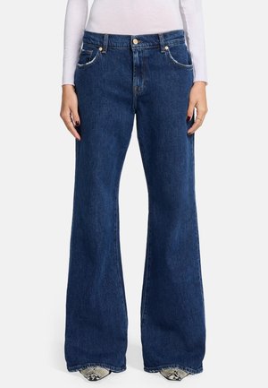 Dark blue flared jeans made from denim, featuring front pockets, a button closure, and contrast stitching along the seams.