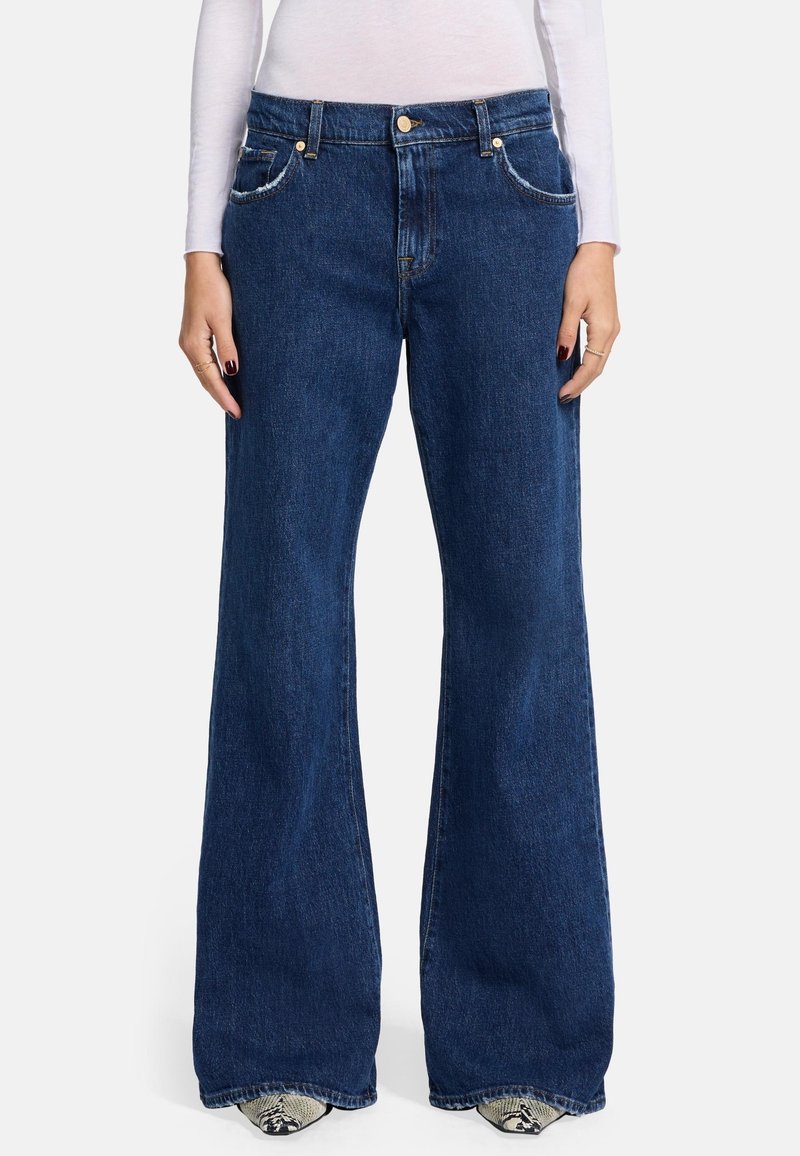 Jeans a zampa d'elefante blu scuro realizzati in denim, con tasche frontali, chiusura con bottone e cuciture a contrasto lungo le cuciture.