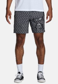 Zwarte zwemshorts met een skull graphic, voorzien van een trekkoord in de taille en zijzakken. Draag er zwarte sneakers met witte sokken bij.