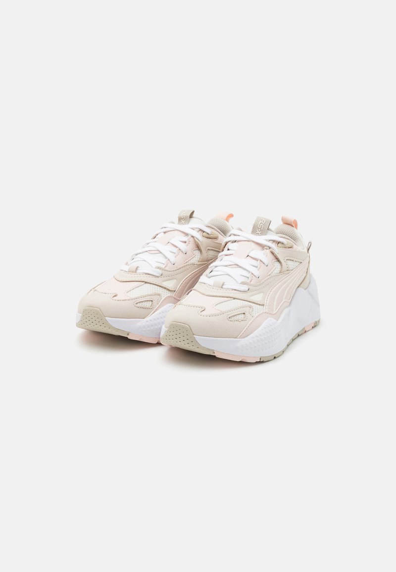 Helle rosa Sportschuhe mit Mesh- und synthetischen Überzügen, runder Zehenpartie, weißen Sohlen und kontrastierenden Akzenten in Beige und Pfirsich.