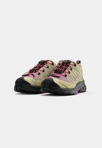 Scarpe da escursionismo beige chiaro con suole nere e dettagli rosa. Presentano un design curvo, pannelli in rete e lacci elastici per una calzata sicura.