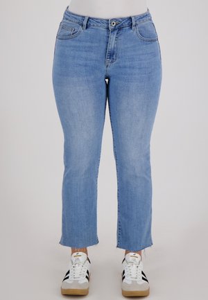 Lichtblauwe denim jeans met een rechte pijp, een middelhoge taille en een rafelige zoom. Gekocht met witte sneakers met zwarte strepen.