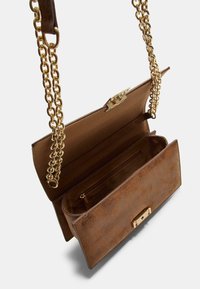 Sac à main en cuir marron avec une bandoulière en chaîne dorée, présentant une texture lisse, une fermeture à clasp et une poche intérieure. Design ouvert.