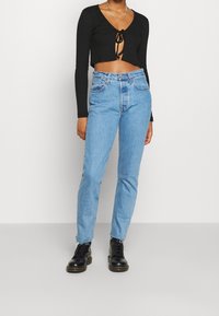 Svart ribbad croppad topp med framslips, kombinerad med ljusblå hög midja jeans, och svarta snörstövlar med tjock sula.