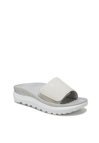 Witte slide sandal met een zachte, gebogen band en een getextureerde voetbed. De zool is grijs met een golfpatroon voor grip en demping.
