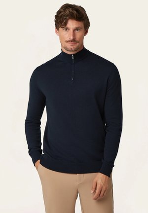 Navy zip-neck sweater made of smooth fabric. Features long sleeves and a ribbed hem and collar for a fitted design. Minimalist aesthetic.