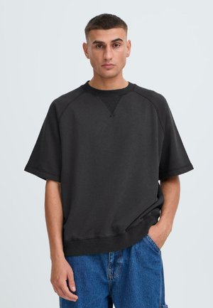 Felpa nera oversize realizzata in tessuto morbido, con colletto rotondo, maniche corte e dettagli a coste sul colletto e sull'orlo.