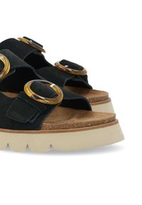 Sandali neri in suede con due grandi accenti circolari color ambra, un letto in sughero e una suola spessa di colore crema con un motivo a onda.