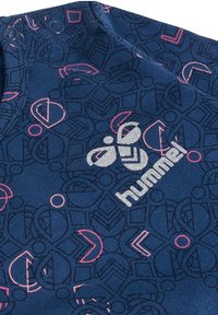 Marinblått tyg med ett geometriskt mönster i rosa, med en silverfärgad "hummel"-logotyp. Inkluderar två tryckknappar på axeln.