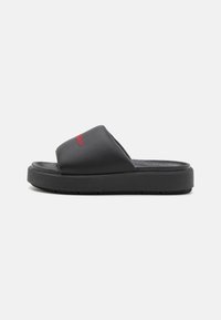 Black slides with a textured rubber sole, featuring a smooth upper and red embroidery. The design is open-toed with a low profile.