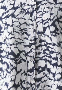 Camicia button-up con un motivo astratto blu navy e bianco, realizzata in un tessuto testurizzato, con cinque bottoni sul davanti.