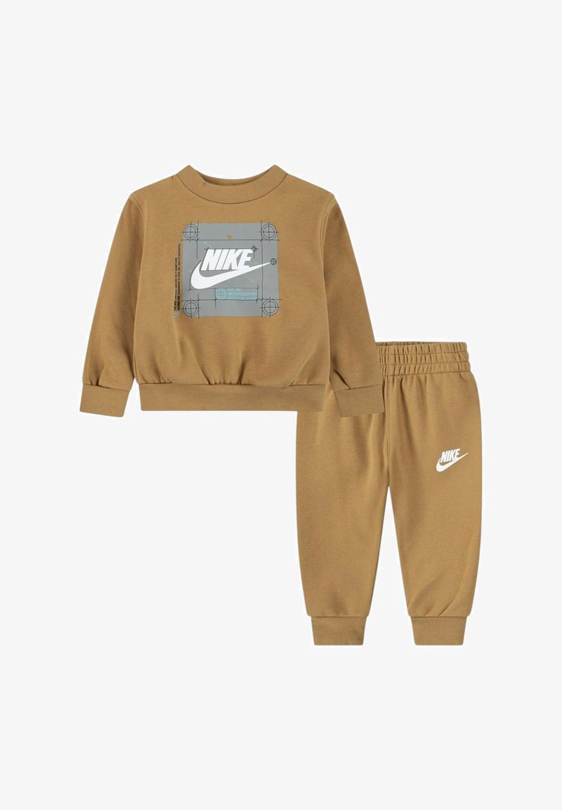 Set di felpa e pantaloni marroni Nike. La felpa presenta una grafica del logo grigia; i pantaloni hanno una cintura elastica e un dettaglio del logo bianco sulla gamba.