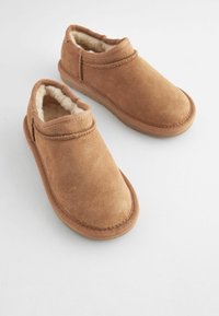 Scarpe slip-on in suede marrone con morbida fodera in pelliccia e dettagli cuciti; punta arrotondata e suola in gomma per comfort e supporto.