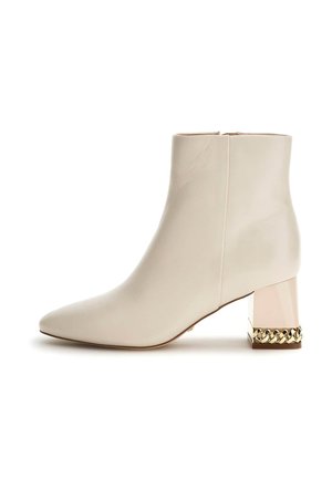 Stivale ankle bianco in pelle con punta appuntita, tacco blocco decorativo in oro e trasparente e superficie liscia. Chiusura a zip sul retro.
