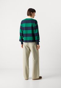 Gestreepte poloshirt met lange mouwen in groen en marineblauw, van een katoenmengsel, met een witte kraag. Gecombineerd met relaxte, lichtgekleurde broeken en bruine schoenen.
