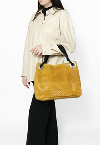 Borsa a tracolla gialla intrecciata con una finitura tessurizzata, dotata di manici neri e occhielli dorati. La borsa ha una forma rettangolare e un design spazioso.