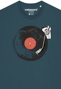 T-shirt teal avec un graphique d'un disque vinyle au centre orange, un bras de platine blanc et une surface noire texturée.