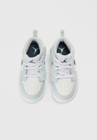 Αθλητικά παπούτσια με λευκή δερμάτινη μύτη, πλευρές από ανοιχτό μπλε δέρμα και σκούρες μπλε λεπτομέρειες. Διαθέτουν κλείσιμο με κορδόνια μπροστά  και θηλιά στο πίσω μέρος.