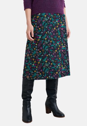Jupe noire à motifs floraux avec des accents turquoise, violet et jaune ; longueur genou, associée à des bottes en cuir noires montantes et un pull violet.