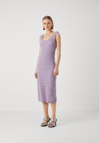 Abito lavorato a maglia color lilla con scollatura a barchetta e orlo a coste. Presenta un motivo testurizzato e una silhouette aderente, abbinato a sandali argentati.