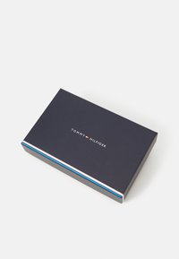 Dark blue rectangular box with a white and red "TOMMY HILFIGER" logo. Features a tricolor stripe accent along the edge. Smooth texture.
