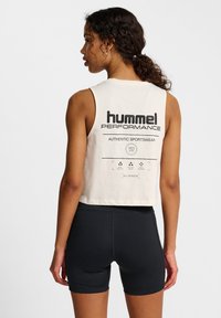 Cropped cream athletic tank top with black logo on the back, paired with black fitted shorts. Smooth fabric, minimalistic design.