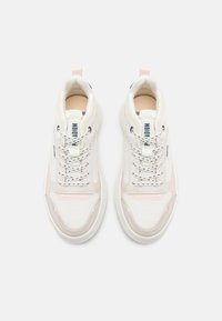 Zapatillas blancas y rosa claro con una parte superior de tela texturizada, punta redondeada, cordones en contraste y una suela de goma. Acentos metálicos en los logos.