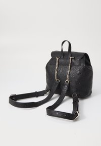 Czarny skórzany plecak z wytłaczanym wzorem, klapą na zakładkę i łańcuszkowymi zdobieniami. Posiada regulowane paski oraz teksturowaną powierzchnię.