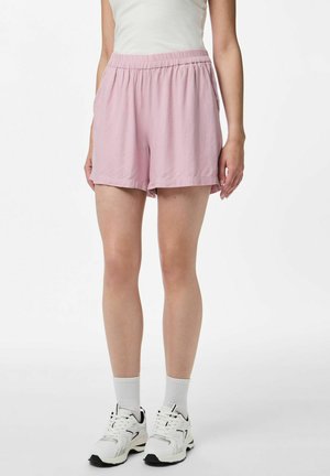 Ljust rosa avslappnade shorts med resårmidja, sidfickor och avslappnad passform, i kombination med vita sneakers och ribbade strumpor.