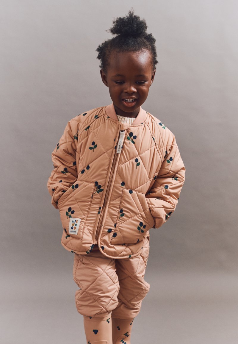 Quilted pink jacket with floral pattern, zip closure, and ribbed collar. Paired with matching pants, both featuring similar designs.