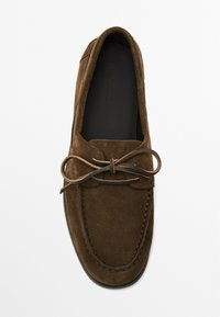Brune ruskinds loafers med en rund toe, en tynd søm og en matchende sløjfedetalje. Glat sort sål synlig nedenunder.