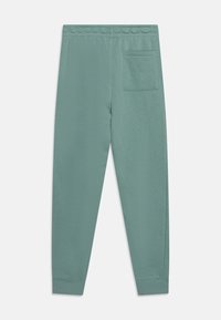 Grönblå sweatpants med elastisk midja och en enda bakficka på höger sida, visade platta på en vit bakgrund.