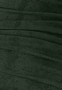 Tmavozelená textúrovaná tkanina s ryhľovaným vzorom, s jemným leskom a miernym splývaním, naznačuje mäkký a flexibilný materiál.