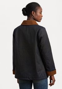 Black jacket with a brown corduroy collar and cuffs. Features a straight cut and long sleeves. Smooth texture, partially quilted lining.