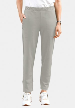 Lichtgrijze broek met een rekbare tailleband, zijzakken met rits, slim fit en taps toelopende enkels, gecombineerd met witte sneakers.
