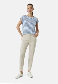 Gestreiftes blau-weißes Kurzarmhemd kombiniert mit beigen Hosen und weißen Sneakers. Einfaches Design mit lockerer Passform und ohne sichtbare Muster.