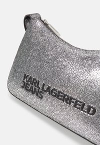 Silver crackle-textured handbag featuring a black logo reading "KARL LAGERFELD JEANS" and a zip closure at the top.