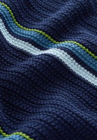 Pătură textilă tricotată, cu bază de culoare bleumarin închis, având dungi orizontale în albastru deschis, alb și verde. Aspect texturat și moale.