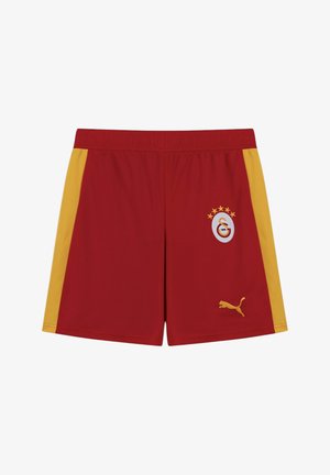 Pantaloncini sportivi rossi con strisce laterali gialle, emblema del Galatasaray con stelle sulla gamba destra e logo Puma giallo sulla gamba sinistra.