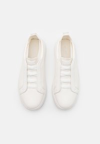 Vita slip-on sneakers med en slät läderutsida, elastisk banddesign, minimalistisk stil och rundade gummisulor.