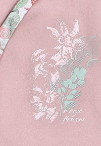 Roze textiel met bloemmotief met roze en groene bloemen. Bevat een knoopdetail en de tekst "magische bloemen" in het wit.