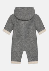 Mono de bebé de felpa gris con capucha, mangas largas y puños color crema en las mangas y piernas.