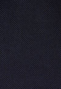 Tekstiilinäidis tumedas tumesinis, tihedalt kootud peene tekstuuriga. Omab ühtlast mustrit, kus kogu pinnal on väikesed üleskerkivad kiud.