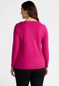 Maglione fucsia a girocollo con maniche lunghe, finiture a coste e orlo. Tessuto morbido, scollatura arrotondata e dettagli di cucitura visibili sulle spalle.