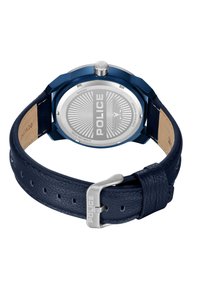 Modra nerjaveča jeklena ura s okroglo ohišjem in vgraviranim zadnjem delom. Ima temno modro usnjeno zanko s teksturirano površino in srebrno kovinsko opremo.